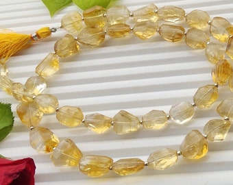 May include: A strand of yellow citrine gemstone beads, faceted and strung on a silver wire. The beads are a light yellow color and have a translucent appearance.