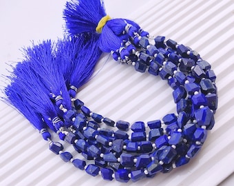 May include: A strand of deep blue lapis lazuli gemstone beads with a faceted, irregular shape. The beads are strung on a silver wire and have a blue tassel at each end.