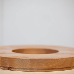 May include: A wooden ring with a large center hole. The ring is made of light brown wood and has a smooth, polished finish.