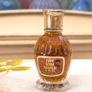 May include: A vintage perfume bottle of "Vivi Wild Musk" with a gold cap and label. The bottle is a warm amber color, with a ribbed design. The label is brown with white text and a black horse graphic. The bottle is 1/2 fl. oz.