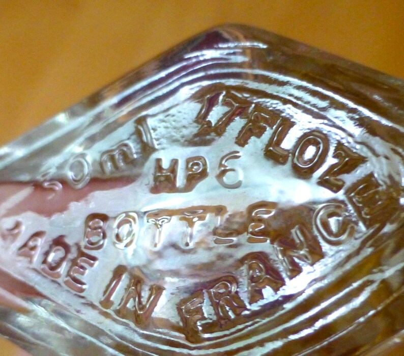 Puede incluir: Una taza de cer&aacute;mica blanca con un asa negra y el texto "But First, Coffee" en negrita negra. La taza se encuentra sobre un fondo borroso, sugiriendo un ambiente acogedor.