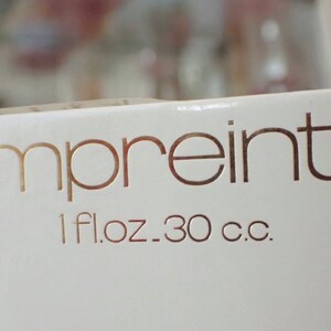 May include: A white box with gold lettering that reads "empreinte" and "1 fl.oz. 30 c.c."