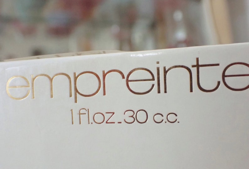 May include: A white box with gold lettering that reads "empreinte" and "1 fl.oz. 30 c.c."