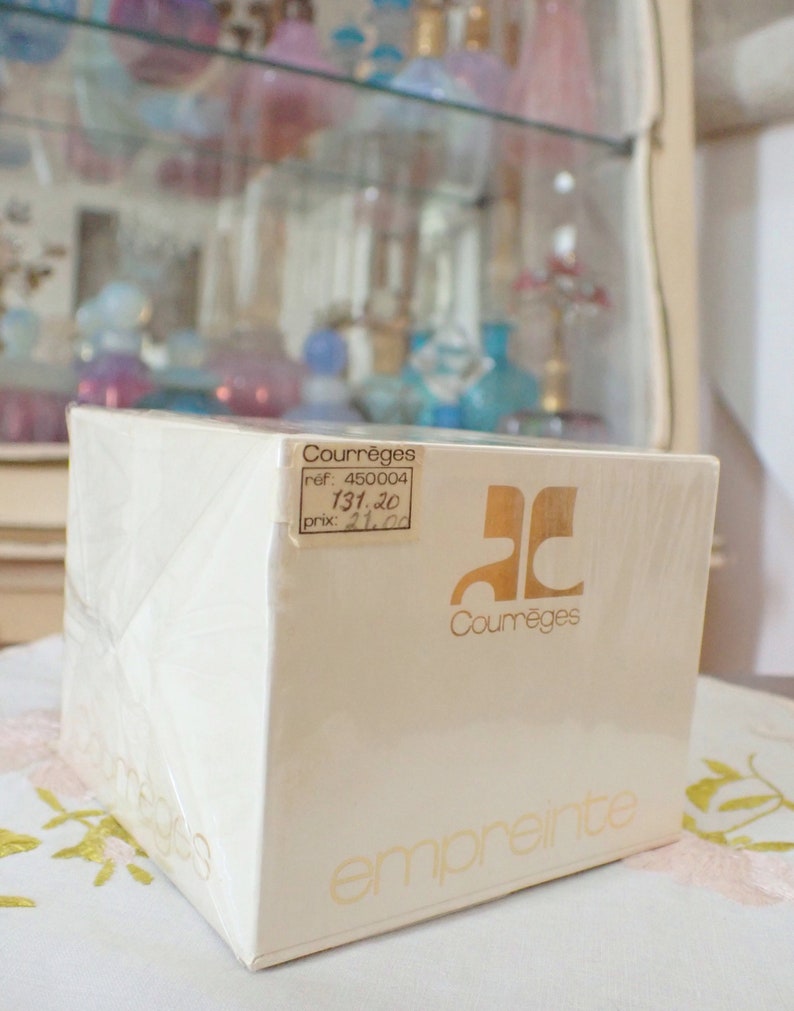 May include: A white box with gold lettering for a Courr&egrave;ges Empreinte perfume. The box has a price tag with the text "ref: 450004, 131,20, prix: 21,00".