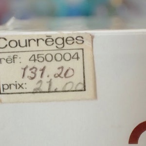 May include: A white box with a price tag that reads "Courr&egrave;ges" with a reference number of "450004" and a price of "131.20" and "21.00".