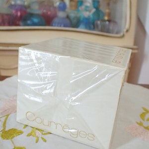 May include: A white box with a clear plastic wrap, the box is labeled with the text "Courr&egrave;ges" in gold lettering.