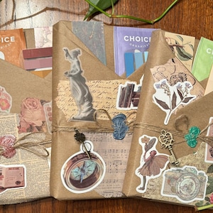 May include: Three wrapped packages with a vintage aesthetic. Each is wrapped in brown paper and adorned with stickers, twine, and wax seals. The packages contain bookmarks and decorative elements, with a focus on a classic, antique theme.