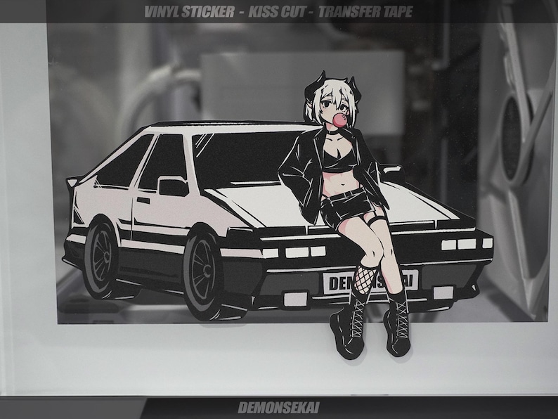 May include: A black and white illustration of a car with a female anime character sitting on the hood. The character is wearing a black leather jacket, a black skirt, and fishnet stockings. The car has the text "DEMONSEIKAI" on the back.
