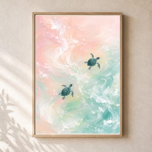 May include: A framed wall art print featuring two dark teal sea turtles swimming through a swirling, abstract background of soft pastel pink, peach, and mint green colours that resemble ocean waves or clouds in a light wooden frame.