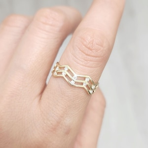 May include: A gold ring with a wavy design and small clear stones.