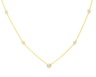 May include: A delicate gold chain necklace with five small round clear stones.