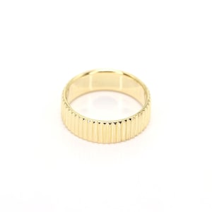 Puede incluir: Un anillo de color dorado con una banda texturizada y estriada.