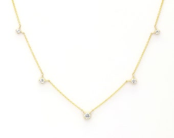 May include: A delicate gold chain necklace with five small round diamonds hanging from it. The diamonds are evenly spaced along the chain.