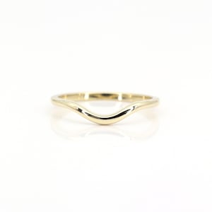 Op de afbeelding: Een eenvoudige gouden ring met een gebogen, golvend ontwerp. De ring is glad en gepolijst.