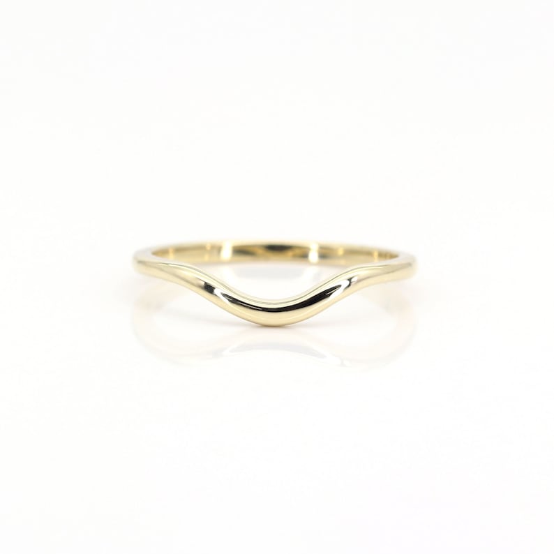 Op de afbeelding: Een eenvoudige gouden ring met een gebogen, golvend ontwerp. De ring is glad en gepolijst.