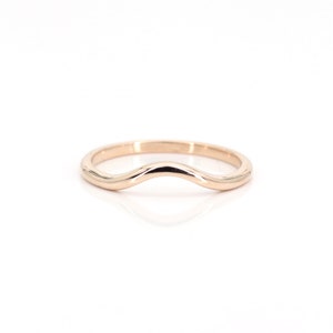 Op de afbeelding: Een gecontourde trouwring van ros&eacute;goud met een gebogen, golvend ontwerp.