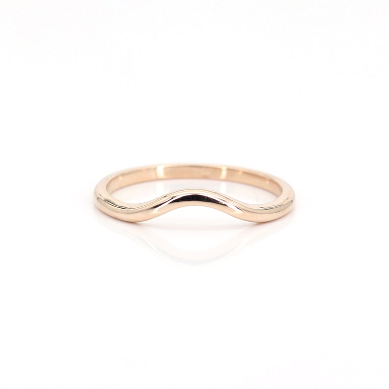 Op de afbeelding: Een gecontourde trouwring van ros&eacute;goud met een gebogen, golvend ontwerp.