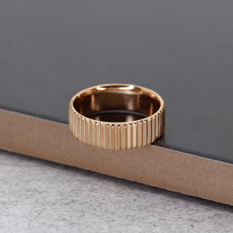 Puede incluir: Un anillo de oro rosa con una banda texturizada y estriada.