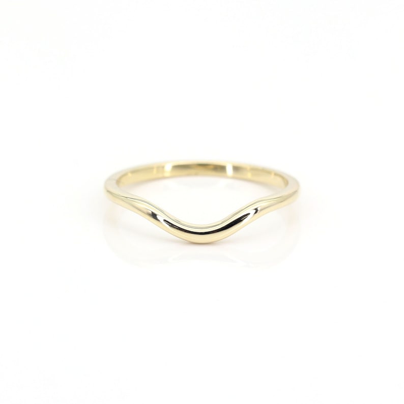 Op de afbeelding: Een eenvoudige gouden ring met een gebogen, golvend ontwerp.