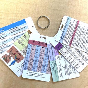May include: A set of medical reference cards on a metal ring, featuring color-coded charts for weight conversion in lbs and kg, pulse oximetry, temperature ranges, vital signs by age, and a 12-lead EKG diagram with Spanish and English text.