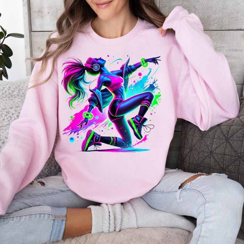 K&ouml;nnte beinhalten: Rosaer Sweatshirt mit einem Grafikdruck einer Frau in einem neon-gr&uuml;nen, blauen und rosa Outfit, die tanzt. Die Frau tr&auml;gt Kopfh&ouml;rer und hat langes, flie&szlig;endes Haar.