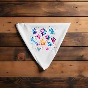 May include: White fabric with a colorful watercolor design of paw prints. The paw prints are in shades of blue, purple, orange, and pink.
