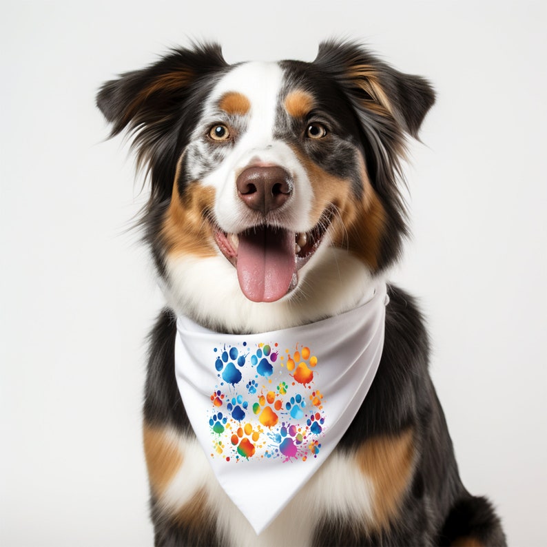 May include: A tri-colored dog wearing a white bandana with a colorful paw print pattern. The bandana has a white background with rainbow paw prints.