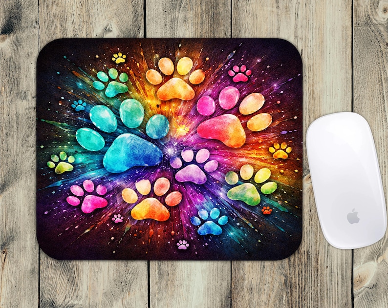May include: A rectangular mousepad featuring a vibrant, colorful design of paw prints in a radial pattern. The paw prints are in shades of blue, green, yellow, orange, and pink, set against a dark background. A white computer mouse is on the right.