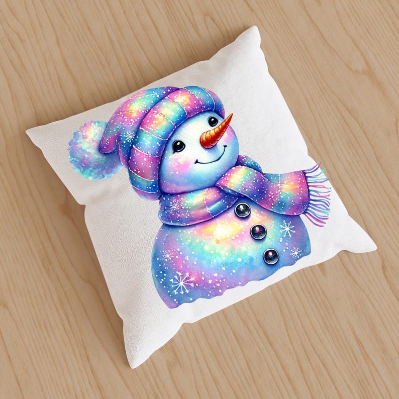 May include: A white cushion with a colourful illustration of a snowman wearing a striped hat and a sparkly scarf. The snowman has a carrot nose and black eyes.
