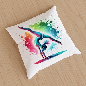 May include: A white cushion featuring a colourful illustration of a gymnast performing a handstand. The background is a watercolour-style design with splashes of pink, blue, green, and yellow.