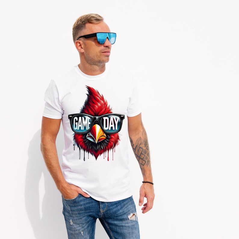 May include: White t-shirt featuring a red cardinal wearing sunglasses with the text "GAME DAY" printed on the front.