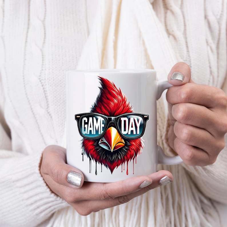 May include: White ceramic coffee mug featuring a red cardinal wearing sunglasses and the text "GAME DAY".