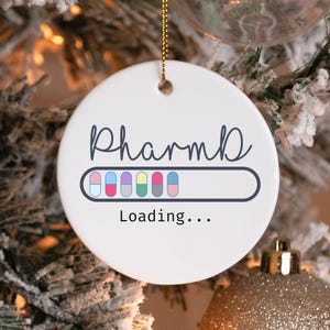 May include: White ceramic Christmas ornament with the text "PharmD" and a progress bar filled with colorful pills that reads "Loading..."