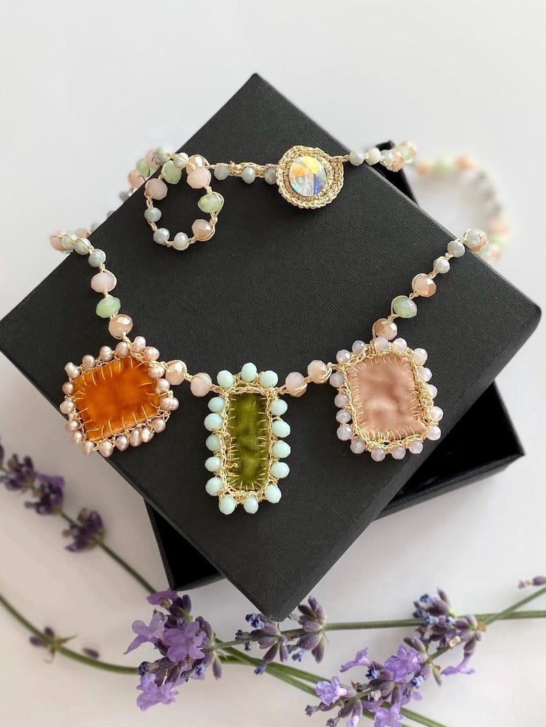 Crochet glass beads necklace is crocheted by hand  with gold thread, small glass beads and embelished with velvet handmade charms. 
It is fastened with crystal button.
Length of necklace is 20,07 inches/51 cm.
