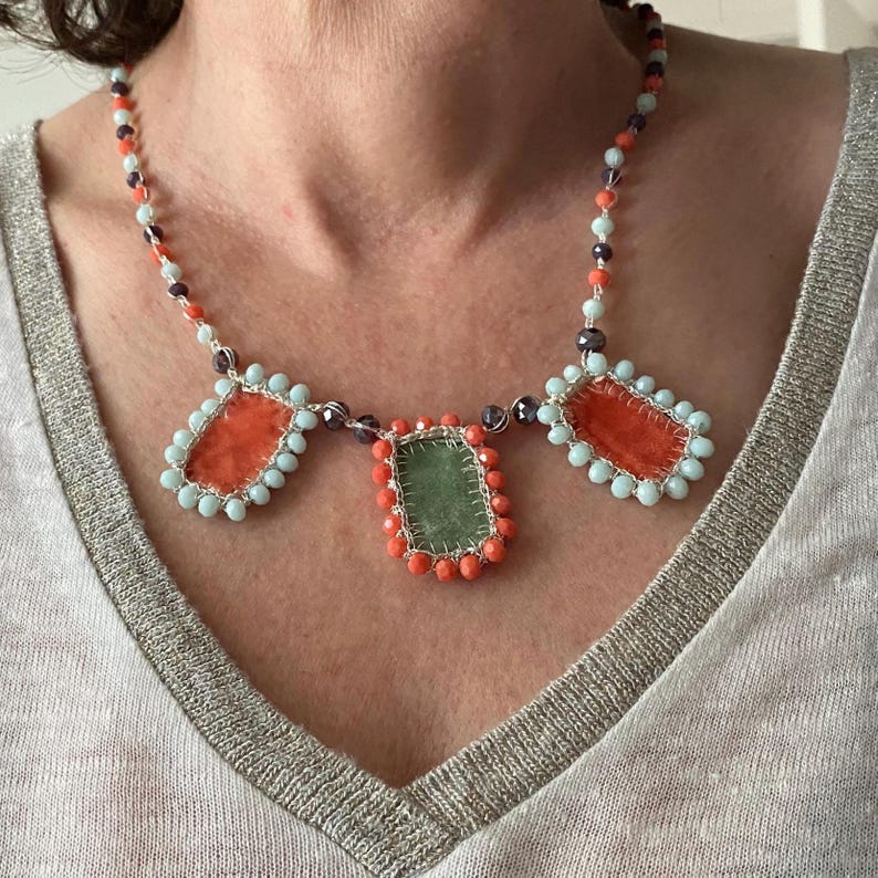 Crochet necklace embellished with three handmade charms made of orange and green velvet.