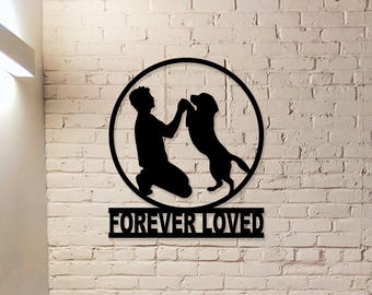 May include: Black metal silhouette of a person and a dog in a circle with the text "FOREVER LOVED" below. The silhouette is on a white brick wall background.