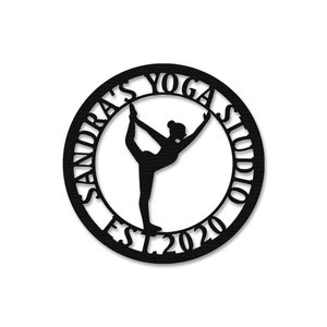 Może przedstawiać: Czarno-biała sylwetka osoby w pozie jogi w środku koła z tekstem "Sandra's Yoga Studio Est 2020" wok&oacute;ł krawędzi.