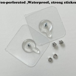 May include: Two clear plastic adhesive hooks with a small metal screw in the center of each hook. There are also three silver metal nuts and two silver metal caps.