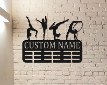 May include: Black metal wall-mounted medal display with five gymnast silhouettes and a personalized nameplate. The display has 12 medal hooks.