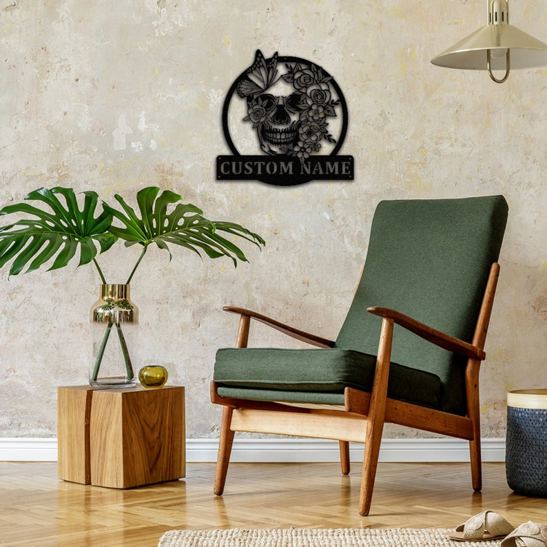 May include: Black metal wall decor featuring a skull with flowers and a butterfly. The skull is surrounded by a circle and the text "CUSTOM NAME" is below the circle.