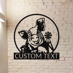 Peut inclure: Décoration murale en métal noir représentant une tête de cochon dans un cercle avec un moulin à vent et une grange en arrière-plan. Le texte "CUSTOM TEXT" est situé sous le cercle.