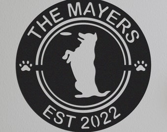 May include: Black and white circular sign with the text "The Mayers Est 2022" and a silhouette of a dog catching a frisbee. The sign has two paw prints on either side.