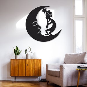 Peut inclure: D&eacute;coration murale en m&eacute;tal noir repr&eacute;sentant une lune croissante avec un visage stylis&eacute; et une figure de Kokopelli debout sur la lune.