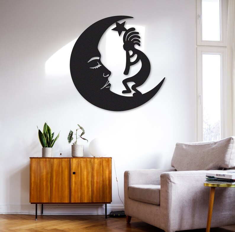 Peut inclure: D&eacute;coration murale en m&eacute;tal noir repr&eacute;sentant une lune croissante avec un visage stylis&eacute; et une figure de Kokopelli debout sur la lune.