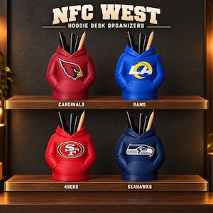 May include: Four hoodie-shaped desk organizers arranged on two shelves. Each features a team logo: Cardinals, Rams, 49ers, and Seahawks. The text reads NFC WEST HOODIE DESK ORGANIZERS. Each organizer holds black pens and a wooden pencil.