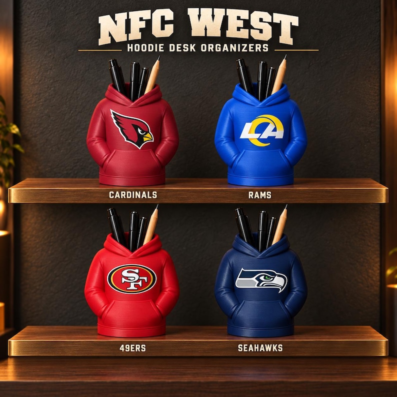 May include: Four hoodie-shaped desk organizers arranged on two shelves. Each features a team logo: Cardinals, Rams, 49ers, and Seahawks. The text reads NFC WEST HOODIE DESK ORGANIZERS. Each organizer holds black pens and a wooden pencil.