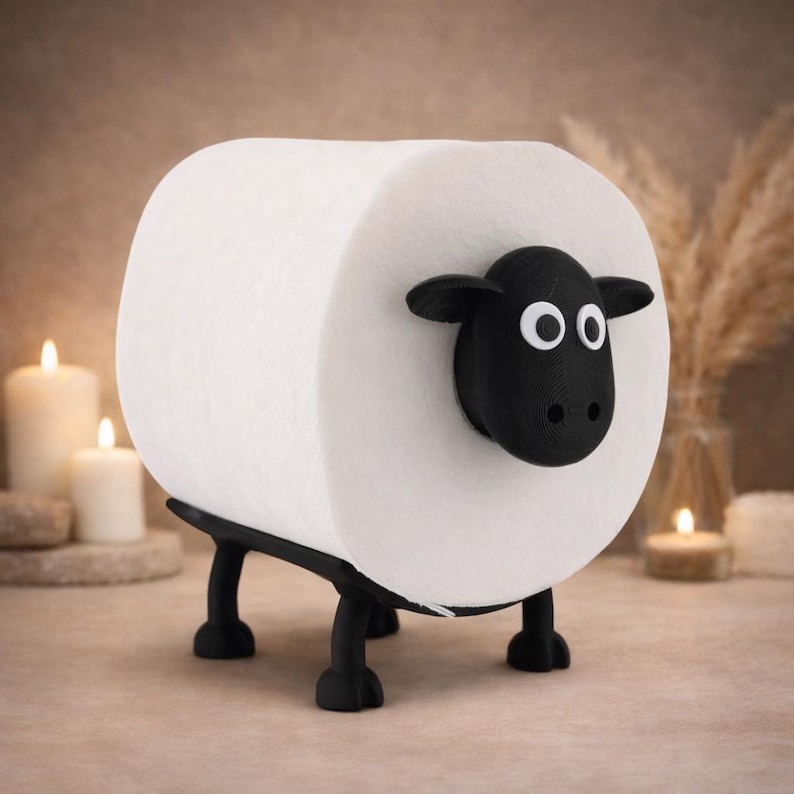 Op de afbeelding: Een grappige toiletpapierhouder in de vorm van een schaap. De witte toiletrol vormt het lichaam van het schaap, met een zwarte kop en poten. De houder is ontworpen om op een oppervlak te staan, wat een leuk element toevoegt aan de badkamerinrichting.
