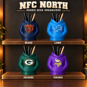 May include: Four hoodie-shaped desk organizers labeled NFC NORTH HOODIE DESK ORGANIZERS. The navy Bears, blue Lions, green Packers, and purple Vikings organizers each hold black pens and a wooden pencil, with team logos printed on the front.