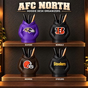 May include: Four hoodie-shaped desk organizers labeled AFC NORTH HOODIE DESK ORGANIZERS. The purple Ravens, black Bengals, brown Browns, and black Steelers organizers each hold pens and pencils, displaying their respective team logos.