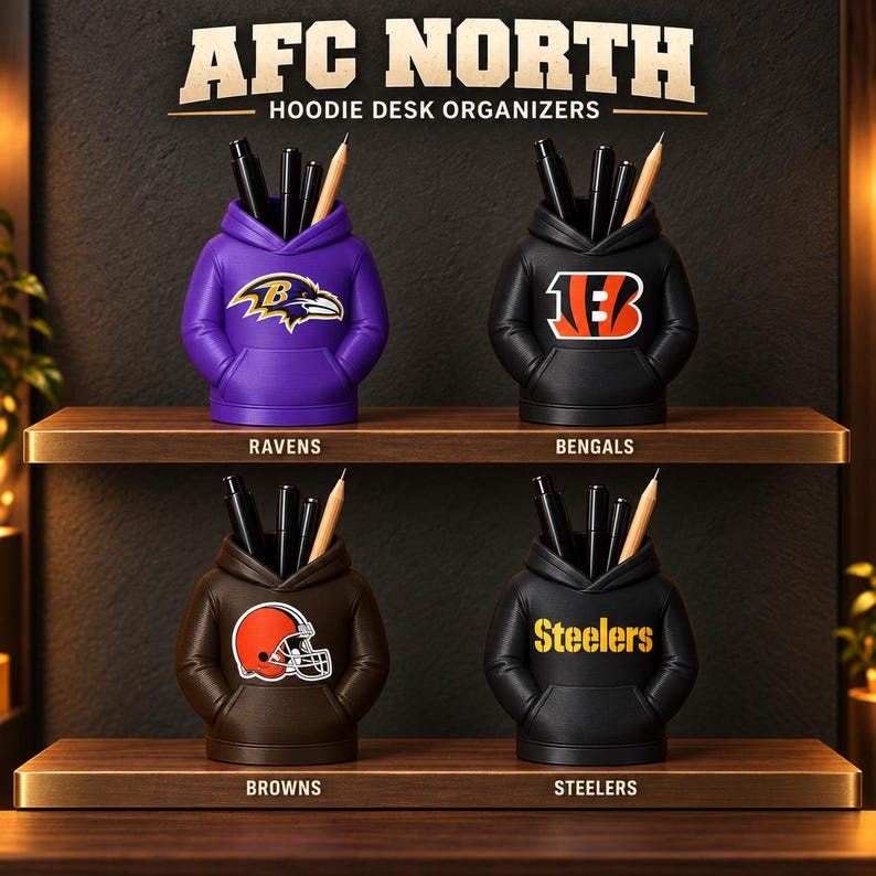 May include: Four hoodie-shaped desk organizers labeled AFC NORTH HOODIE DESK ORGANIZERS. The purple Ravens, black Bengals, brown Browns, and black Steelers organizers each hold pens and pencils, displaying their respective team logos.